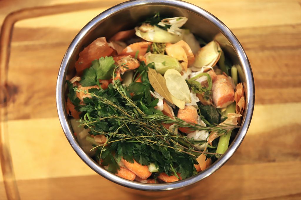 Bone broth with scraps and herbs in the pot