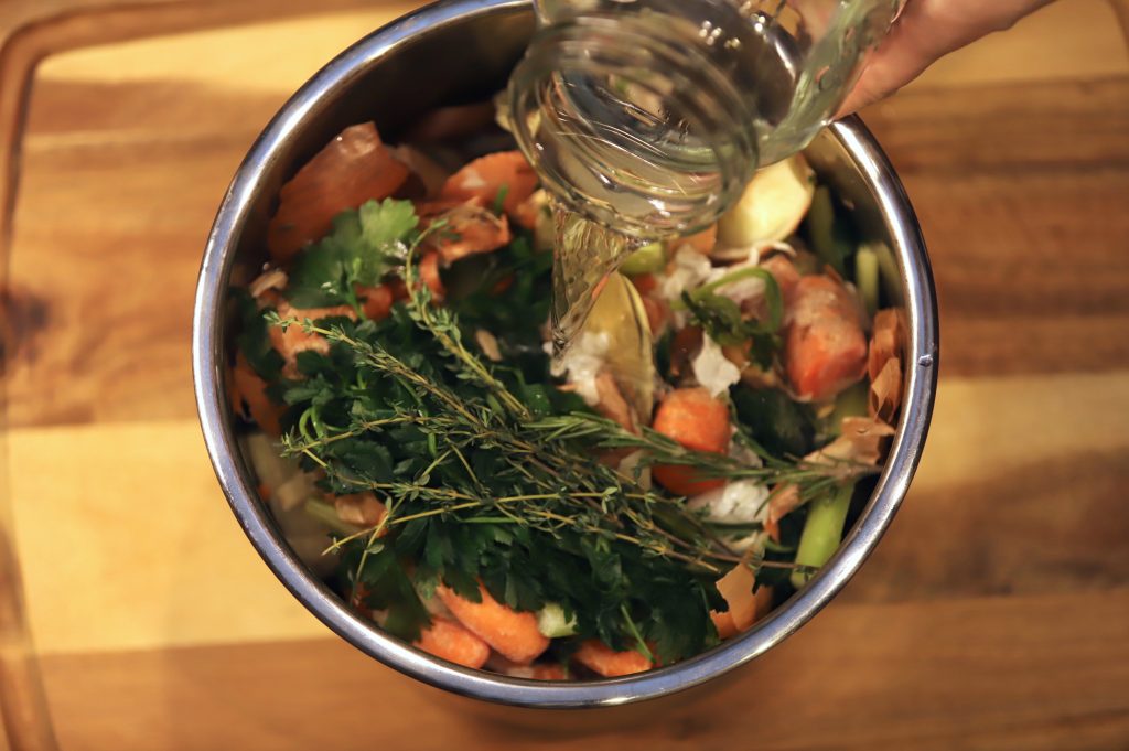 water being poured over bone broth ingredients