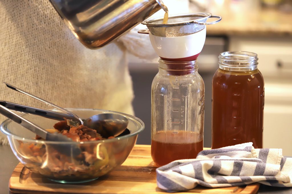 straing bone broth into half gallon glass jars