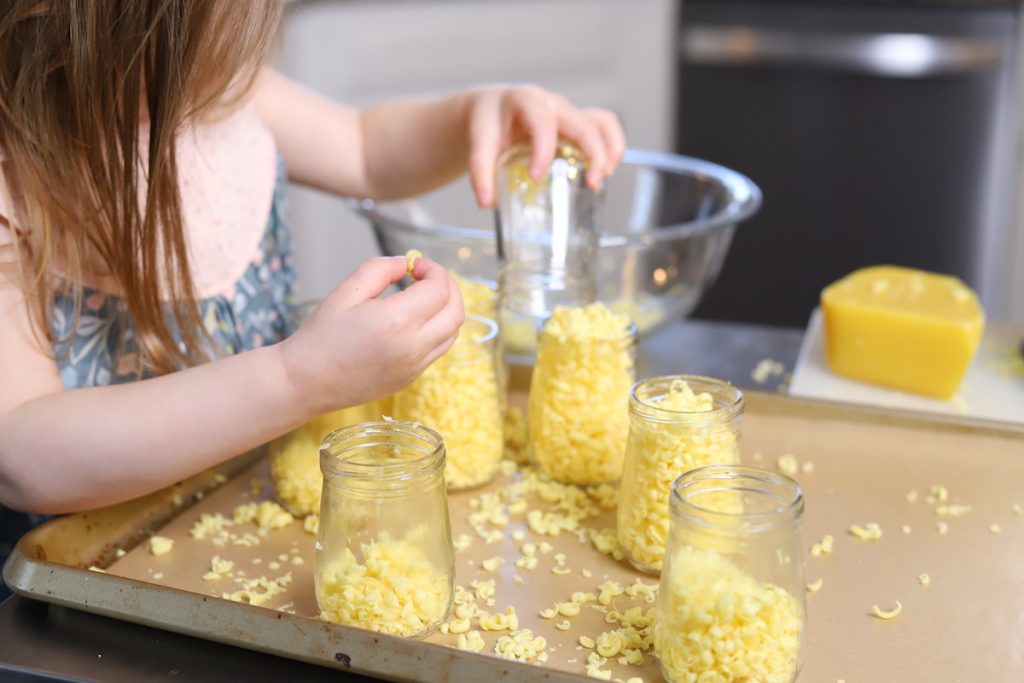 child helping fill jars with beeswax