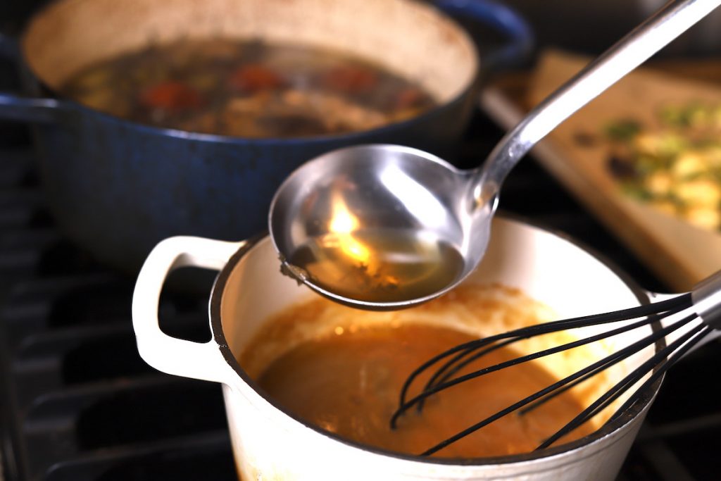 ladeling broth into a pot for gravy
