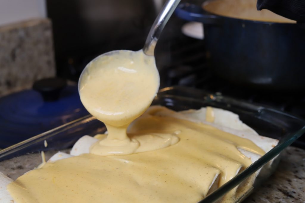 ladeling sauce onto enchiladas