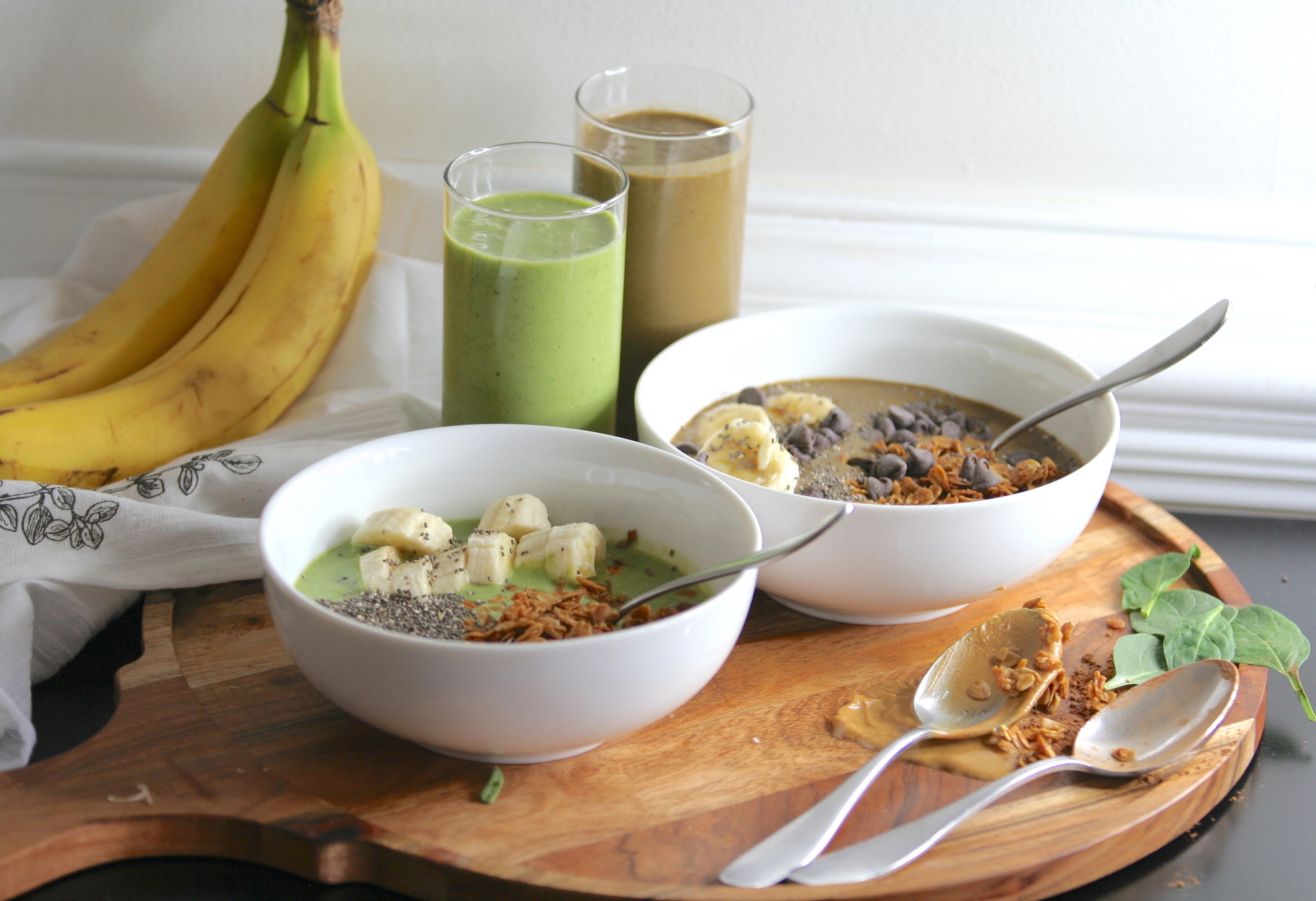 two peanut butter and banana smoothies in glasses and in bowls with toppings